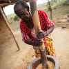 Glorias farmor er ved at banke tørre majskerner. Når skallerne er banket af og siet væk, kan hun sælge majsen ved møllen. Der bliver det malet til mel, som man kan lave ugali af. Foto: Hans Bach.