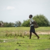 Businge er på vej i skole med sin skoletaske. Han skal gå et par kilometer over markerne for at komme i skole. - Foto: Emmanuel Museruka