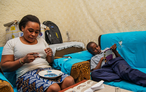 Gift-Mwema-reads-a-book-while-sat-on-a-couch-while-his-mother-does-bead-work-in-Kawangware,-Nairobi,-Kenya.-Victor-Wahome-825x520px.jpg